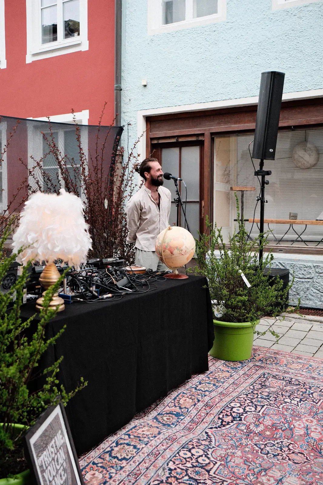Oskabya behind his decks on a street, a rug in front of the table
